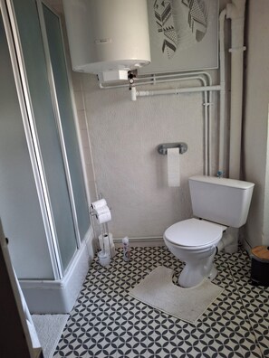 Ein Badezimmer mit Toilette, Handtuchhalter, einer Toilettenrolle und einem gemusterten Boden.