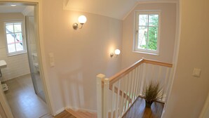 A staircase with a wooden handrail and a potted plant at the bottom. - Vacation home with a fireplace and sauna, about 250 meters from the sandy beach, Wi-Fi, washing machine (Glowe)