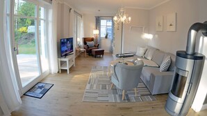 A modern living room with a fireplace, a television, and a sofa. - Vacation home with a fireplace and sauna, about 250 meters from the sandy beach, Wi-Fi, washing machine (Glowe)