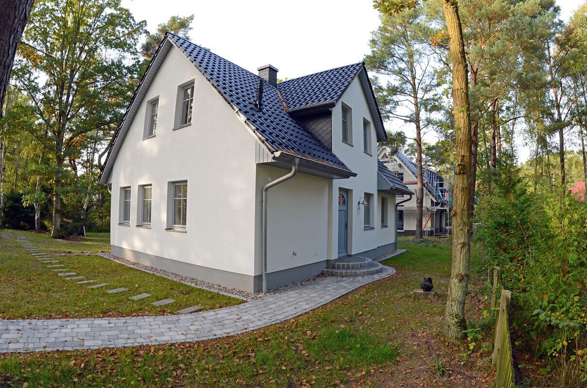 A modern two-story house with a sloped roof, a paved driveway, and a well-maintained lawn.