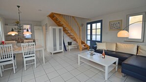 Un salon avec un escalier, un coin repas avec des chaises et une table, et un canapé.