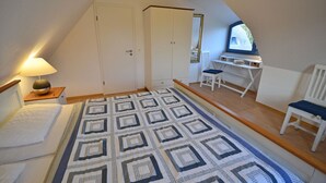 Une chambre à coucher avec un lit, un bureau avec une chaise, une lampe et une fenêtre.
