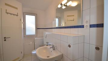 Ein Badezimmer mit einem weißen Waschbecken, einem Spiegel und einem Fenster.