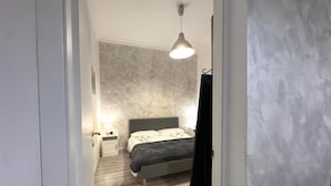 A bedroom with a bed, bedside table, and a hanging light fixture. - AmoR San Lorenzo (Roma)