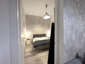 Ein Schlafzimmer mit Bett, Nachttisch und einer Hängelampe.