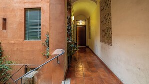 A narrow corridor with a tiled floor, a wooden door at the end, and a window with shutters on the left. - AmoR San Lorenzo (Roma)