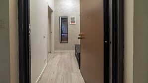 A hallway with a wooden door, a framed picture on the wall, and a light switch on the wall. - AmoR San Lorenzo (Roma)