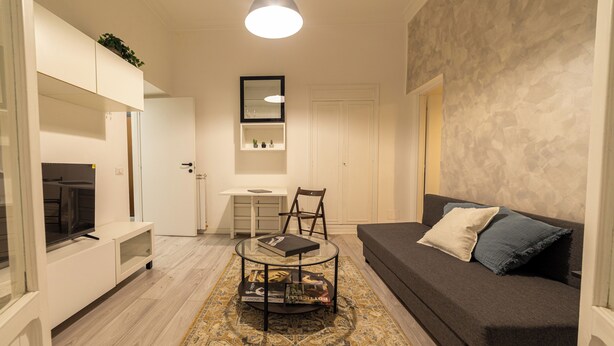A modern living room with a sofa, a coffee table, a TV, and a bookshelf. - AmoR San Lorenzo (Roma)
