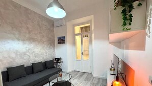 A modern living room with a grey sofa, a round coffee table, and a pendant light. - AmoR San Lorenzo (Roma)