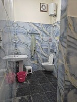 A bathroom with a marble wall, a sink, a toilet, a shower, and a towel rack.