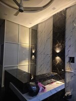 A bathroom with a marble vanity, a ceiling fan, and a wall-mounted light fixture.