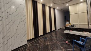 A hotel room with a marble wall, a black tiled floor, a reception desk, and a blue chair. - Prince Hotel (Meerut)