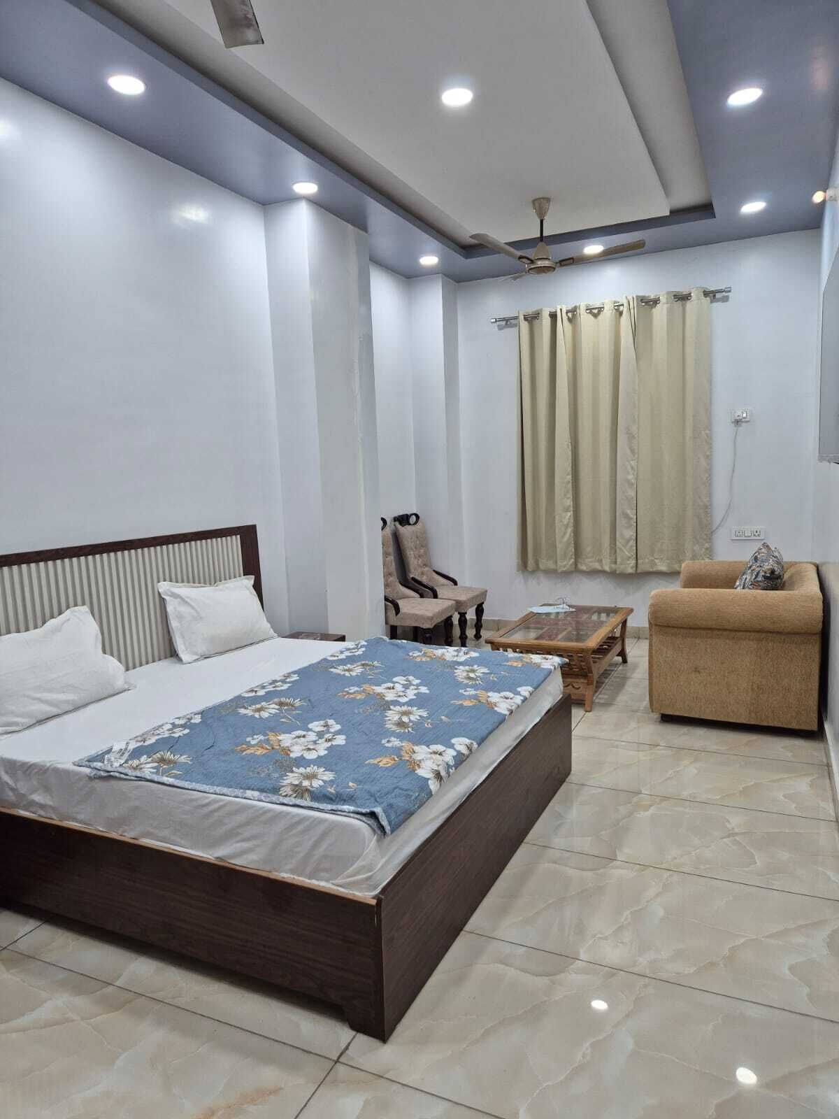 A modern bedroom with a large bed, a chair, a sofa, and a ceiling fan.