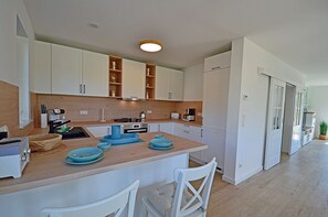 A modern kitchen with white cabinets, a central island with blue plates, and a built-in oven. - House with a fireplace and sauna, about 1,300 m from a sandy beach, 4 bedrooms, sleeps up to 8, Wi-Fi (Glowe)