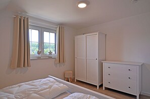 A bedroom with a bed, a wardrobe, a dresser, and a window with curtains. - House with a fireplace and sauna, about 1,300 m from a sandy beach, 4 bedrooms, sleeps up to 8, Wi-Fi (Glowe)