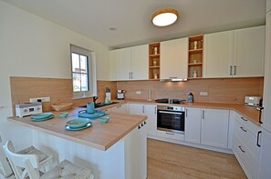 A modern kitchen with white cabinets, a wooden countertop, and a built-in oven. - House with a fireplace and sauna, about 1,300 m from a sandy beach, 4 bedrooms, sleeps up to 8, Wi-Fi (Glowe)