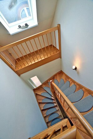 Eine Holztreppe mit Handlauf und einem Fenster darüber.