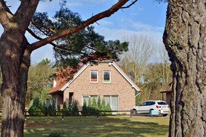 A brick house with a gabled roof, surrounded by trees and a parked car. - Vacation home with a fireplace, about 350 meters from the sandy beach, pets welcome (Glowe)