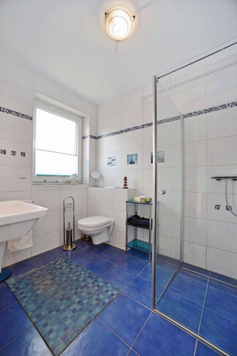 A bathroom with a bathtub, toilet, shower, and a window.