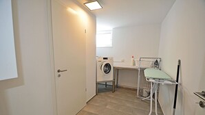 A laundry room with a washing machine, drying rack, and ironing station. - 2-story vacation home, quiet location, about 1.3 kilometers from the sandy beach (Baltic Sea) (Glowe)
