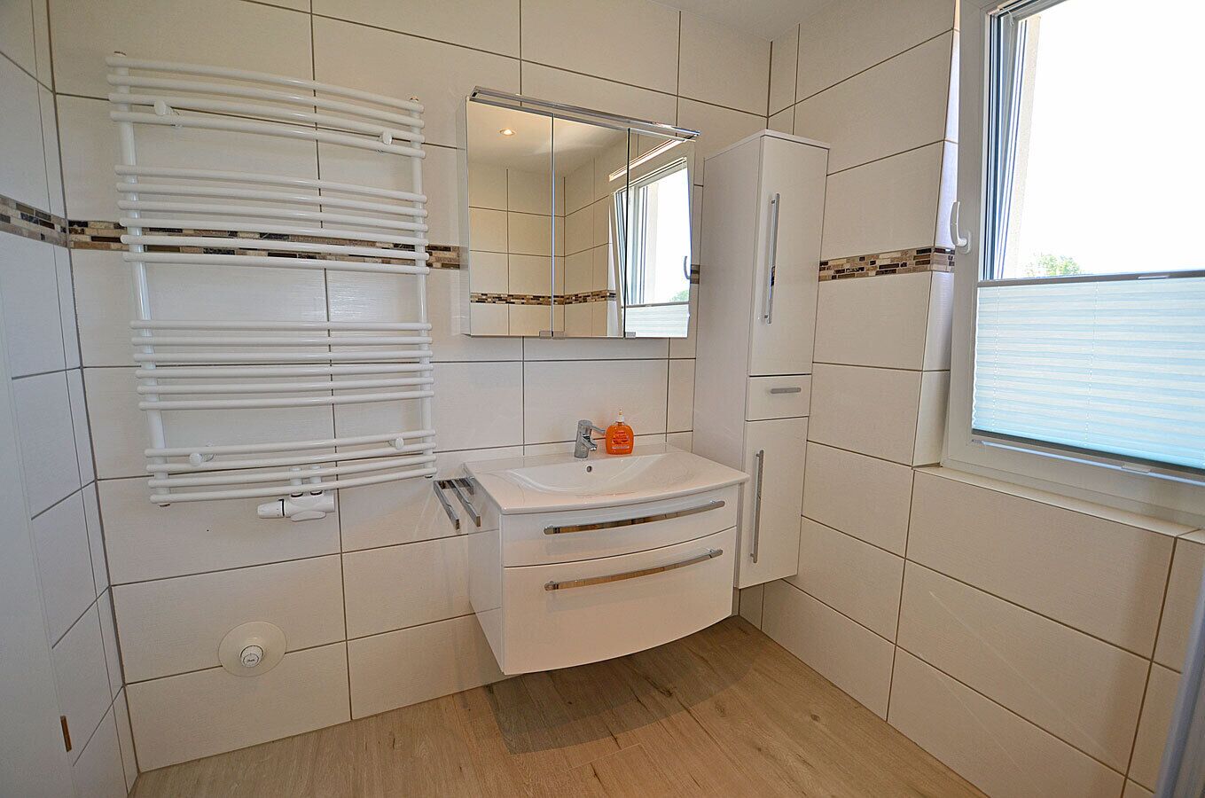 A bathroom with a white sink, mirror, and towel rack.