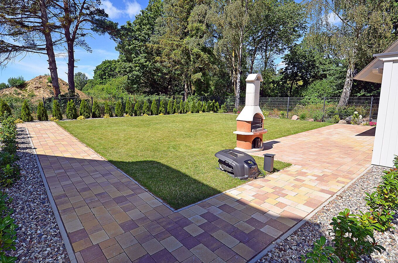 A backyard with a brick patio, a barbecue grill, and a chimney.