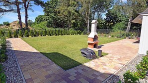 A backyard with a brick patio, a barbecue grill, and a chimney. - 2-story vacation home, quiet location, about 1.3 kilometers from the sandy beach (Baltic Sea) (Glowe)