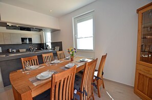 A modern kitchen with a dining area, wooden chairs, and a large window. - 2-story vacation home, quiet location, about 1.3 kilometers from the sandy beach (Baltic Sea) (Glowe)