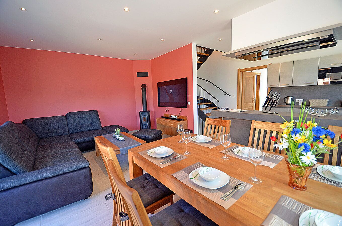 Un salon moderne comprenant un canapé, une table à manger pour quatre personnes et un coin cuisine avec une cuisinière et des placards.