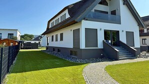 A modern two-story house with a sloped roof, a front entrance with steps, and a paved driveway. - Modern vacation rental with a fireplace, about 1,300 meters from the sandy beach, 3 bedrooms, sleeps up to 6 people (Glowe)
