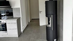 A modern kitchen with a built-in oven and a black vertical appliance, possibly a water heater, in a hallway with a door leading to another room. - Modern vacation rental with a fireplace, about 1,300 meters from the sandy beach, 3 bedrooms, sleeps up to 6 people (Glowe)