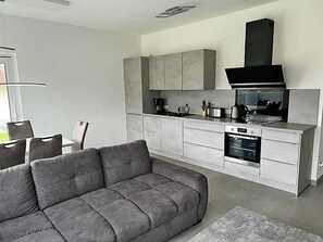 Eine moderne Küche mit grauen Schränken, einem eingebauten Backofen und einer schwarzen Dunstabzugshaube.