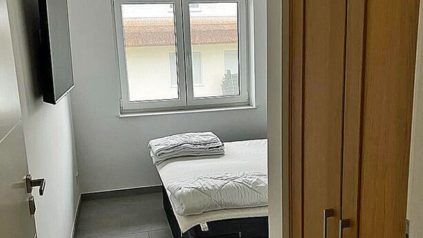 A bedroom with a bed, a window, a wardrobe, and a television on the wall. - Modern vacation rental with a fireplace, about 1,300 meters from the sandy beach, 3 bedrooms, sleeps up to 6 people (Glowe)