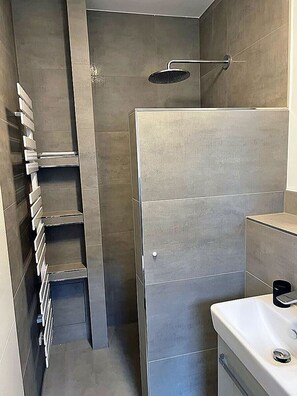 Een moderne badkamer met douche, toilet en een ingebouwde plank.