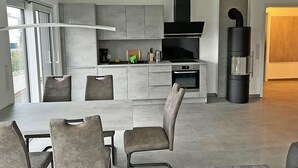 Una cocina moderna con una isla central, electrodomésticos integrados y un comedor con sillas.