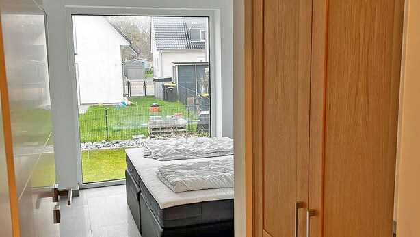 Un dormitorio con cama, armario de madera y vistas al exterior.