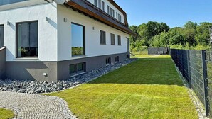 Una casa moderna de dos pisos con entrada pavimentada y césped cuidado.