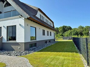 A modern two-story house with a paved driveway and a well-maintained lawn. - Modern vacation rental with a fireplace, about 1,300 meters from the sandy beach, 2 bedrooms, sleeps up to 5 people (Glowe)