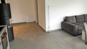 Una sala de estar moderna con un sofá gris, un mueble negro y una pared blanca.