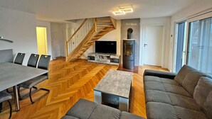 A modern living room with a herringbone floor, a staircase, a fireplace, and a television. - Modern vacation rental with a fireplace, about 1,300 meters from the sandy beach, 3 bedrooms, sleeps up to 6 people (Glowe)