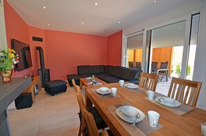 Ein modernes Wohnzimmer mit Essbereich, einer Couch und einem Fernseher.