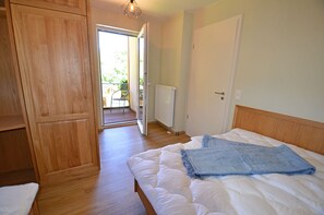 Ein Schlafzimmer mit einem Bett, einem Holzschrank, einer Heizung und einer Tür zu einem Außenbereich.