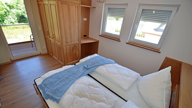 A bedroom with a bed, wooden wardrobe, and skylights. - 2-story vacation home, quiet location, about 1.3 kilometers from the sandy beach (Baltic Sea) (Glowe)