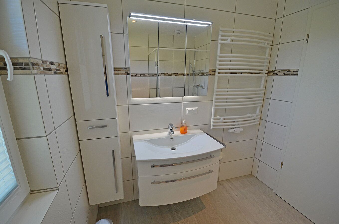 A bathroom with a white sink, mirror, and towel rack.