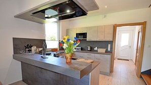 A modern kitchen with a central island, a microwave, and a sink. - 2-story vacation home, quiet location, about 1.3 kilometers from the sandy beach (Baltic Sea) (Glowe)