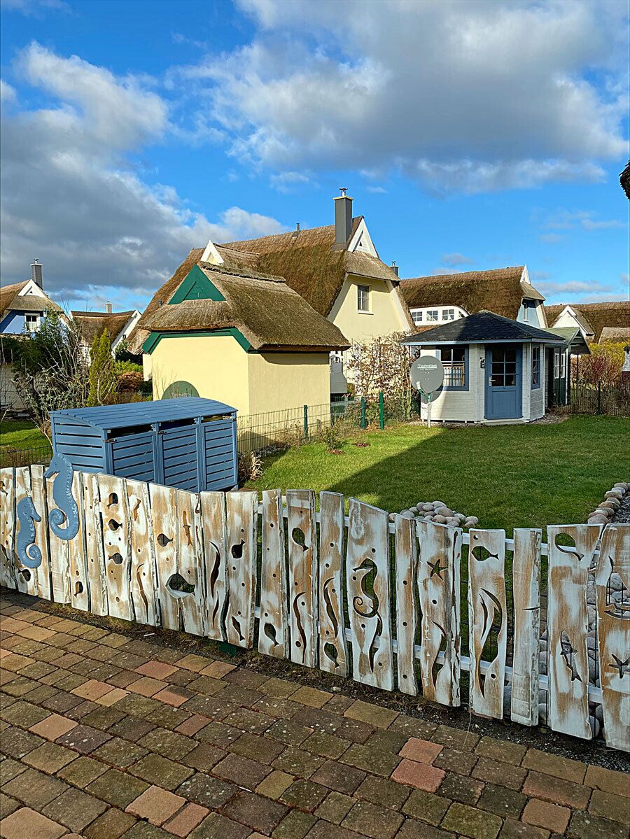 A residential area with houses, a thatched-roof building, and a small shed.