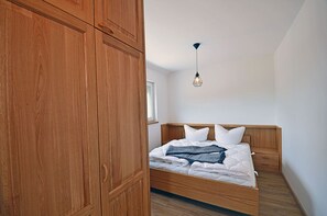 Ein Schlafzimmer mit Holzschrank, Bett mit weißer Bettwäsche und einer Pendelleuchte.