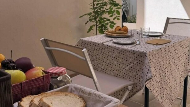 Ein Essbereich mit einem Tisch für zwei Personen, einem Brotkorb und einer Obstschale.
