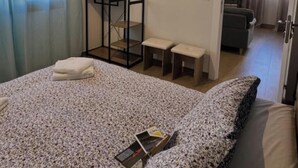 Ein Schlafzimmer mit einem Bett, einem kleinen Tisch, einem Regal und einem Fernseher in der Ecke.