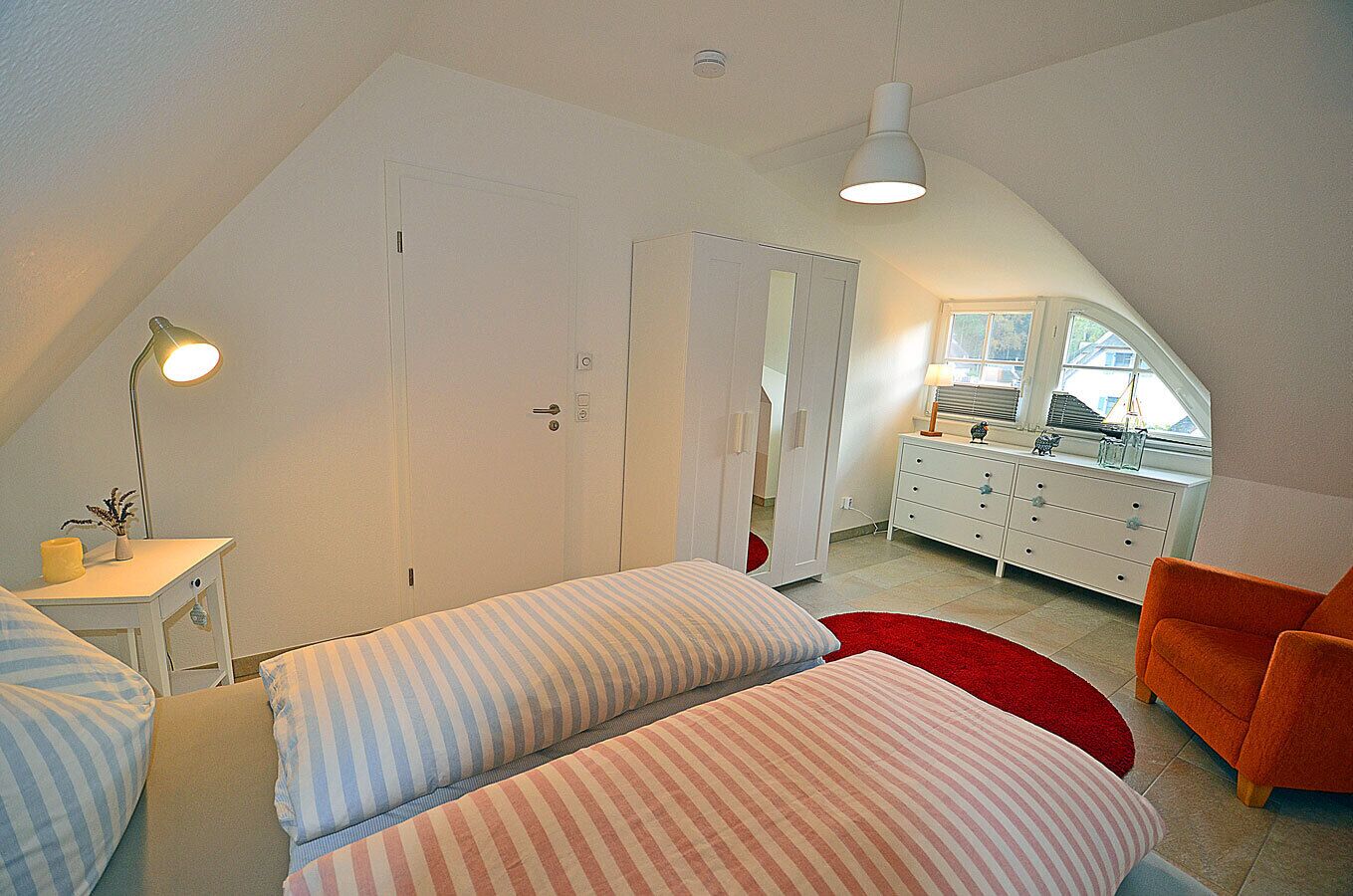 A bedroom with two beds, a desk, a chair, and a dresser.